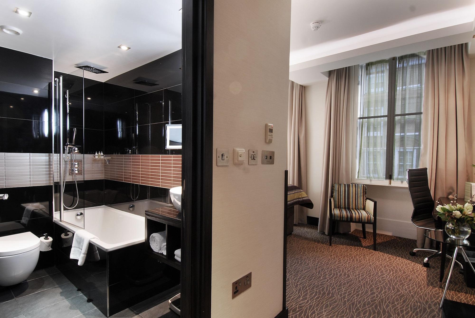 Montcalm Brewery Townhouse Hotel London Ngoại thất bức ảnh The photo shows a modern hotel room that features an elegant bathroom on one side and a living area on the other. 

1. **Bathroom**: The bathroom is stylishly designed with a combination of black and white tiles. It includes a bathtub, a shower area 