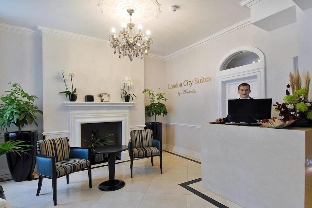 Montcalm Brewery Townhouse Hotel London Ngoại thất bức ảnh The photo shows the interior of a reception area in a hotel called "London City Suites." The space features a light-colored wall with the hotel's name displayed. There is a stylish chandelier hanging from the ceiling, providing warm lighting. 

In th