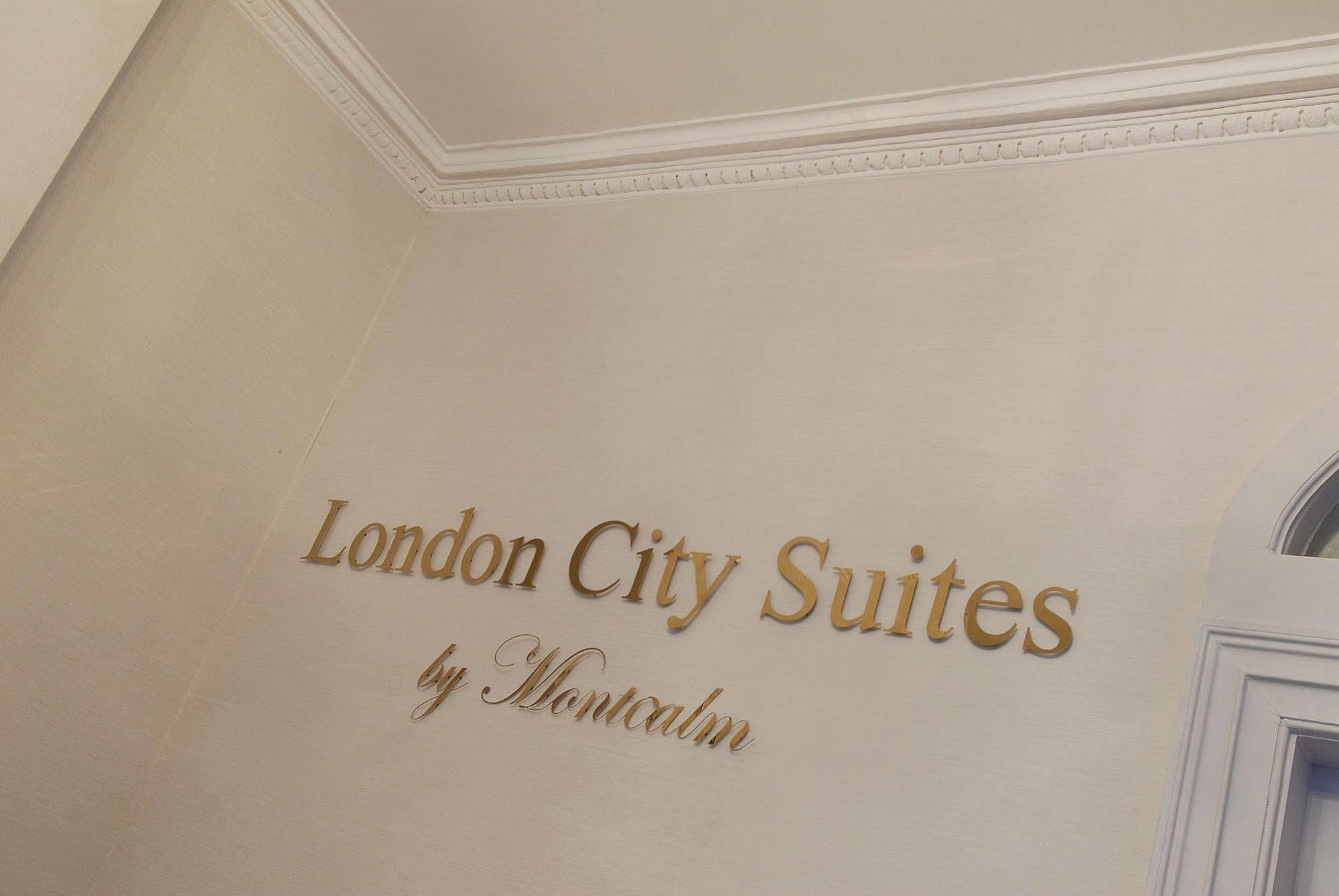 Montcalm Brewery Townhouse Hotel London Ngoại thất bức ảnh The photo shows a wall display featuring the text "London City Suites" in a bold, gold-colored font. Below that, the words "by Montcalm" are written in a smaller, elegant style. The background appears to be a neutral-colored wall, possibly in a hotel