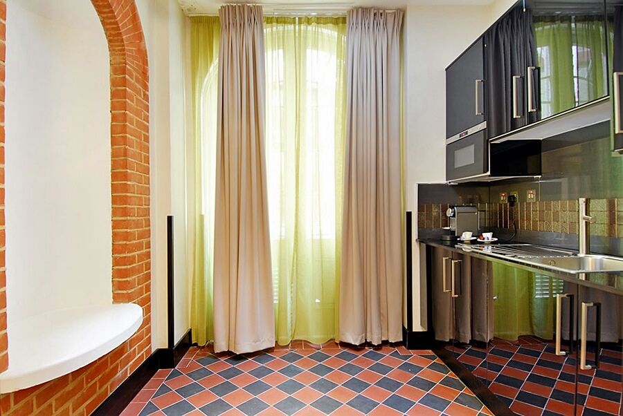 Montcalm Brewery Townhouse Hotel London Ngoại thất bức ảnh The photo shows a kitchen area with modern design elements. There are large, light-colored curtains hanging from the windows, allowing natural light to filter in. The walls are partially exposed brick, giving a warm texture to the room. The flooring 